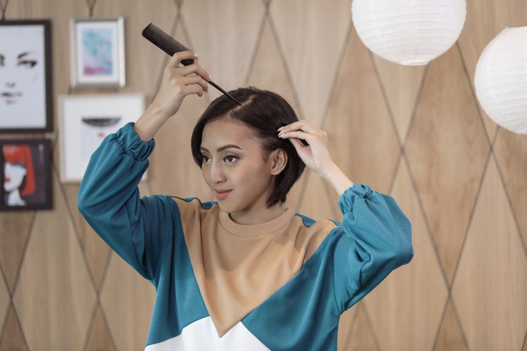 Wanita Asia dengan kepang samping menyemprotkan hairspray