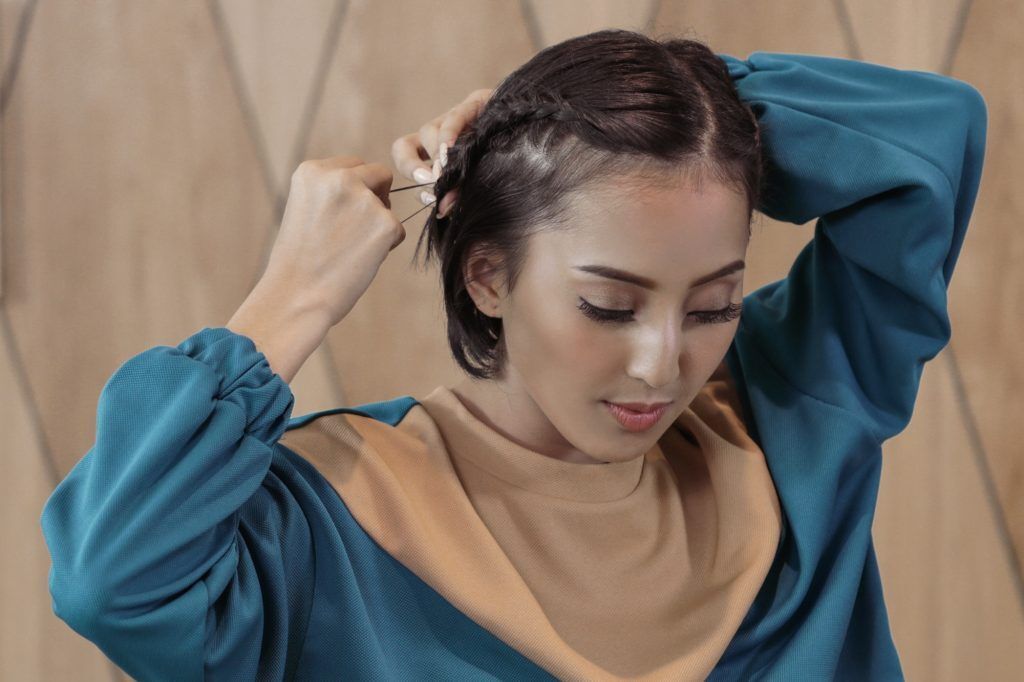 Wanita Asia dengan kepang samping menyemprotkan hairspray