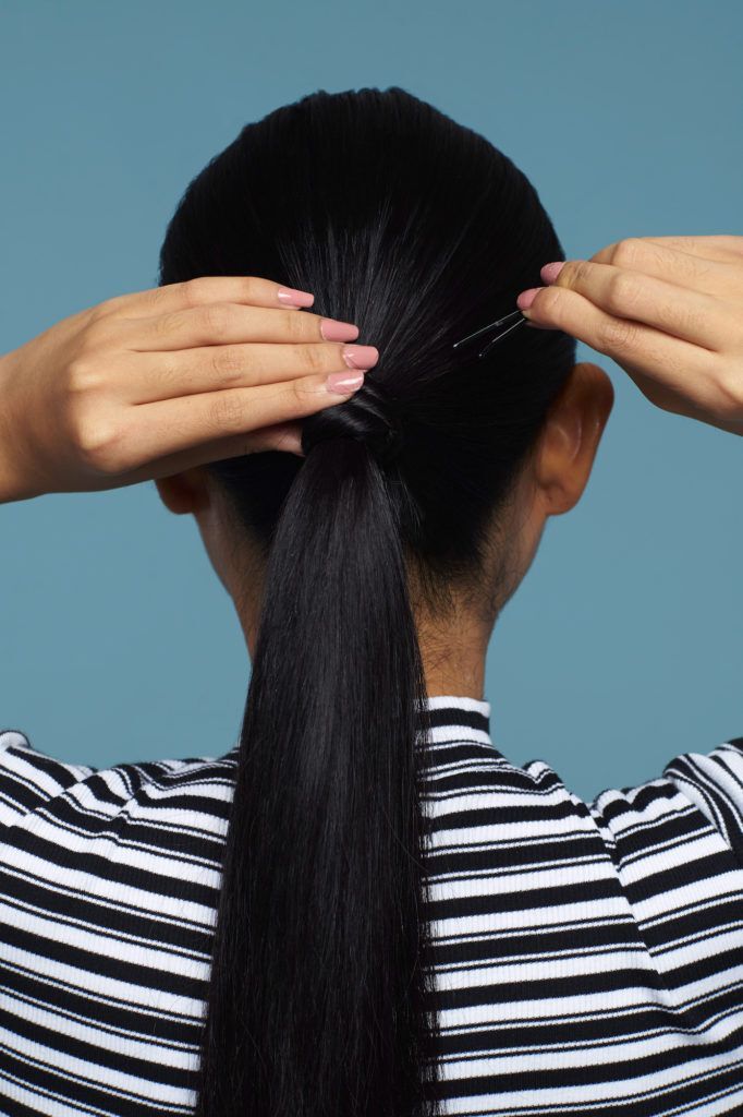 Wanita asia dengan rambut hitam lurus panjang menata ponytail.
