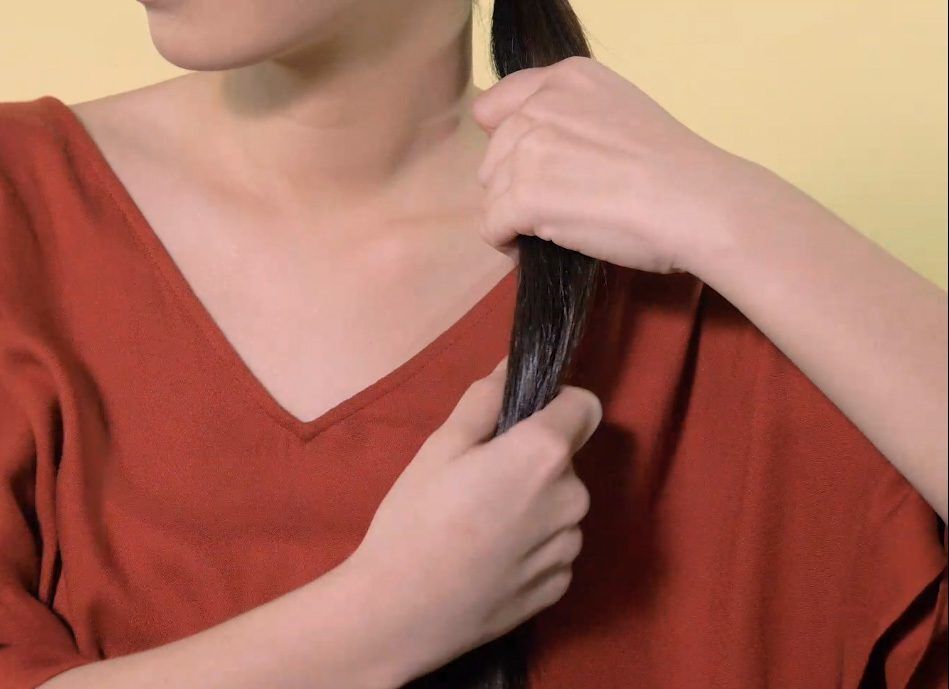 Wanita Asia merapikan rambut ponytail.