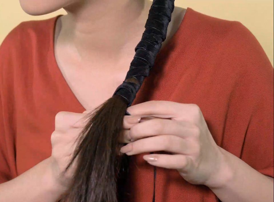 Wanita Asia menggulung ponytail dengan pita untuk gaya wrapped ponytail.