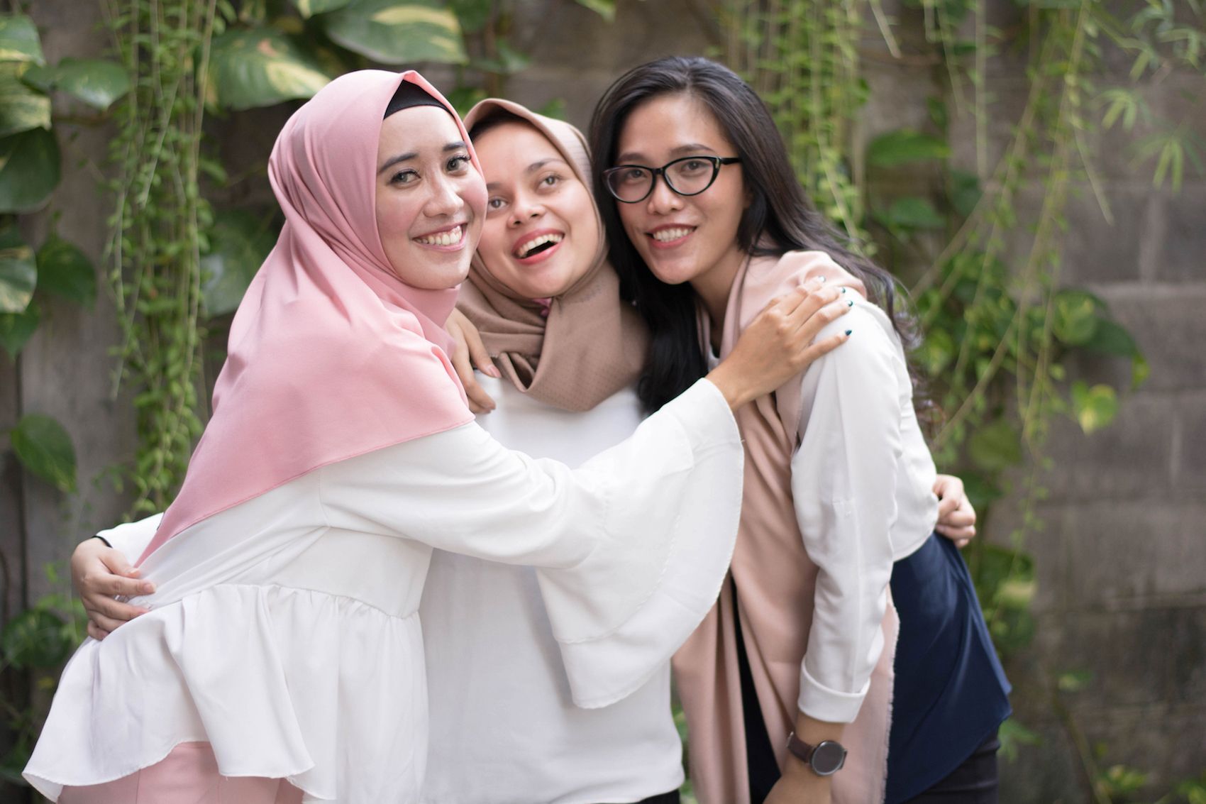 Tiga wanita asia dengan dua hijab dan satu tanpa hijab tersenyum ke kamera