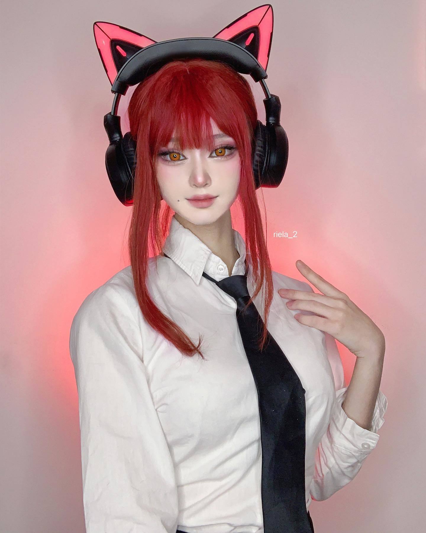 Wanita Asia sedang cosplay menjadi seorang karakter anime berambut merah dan memakai headphone berdetail telinga kucing.