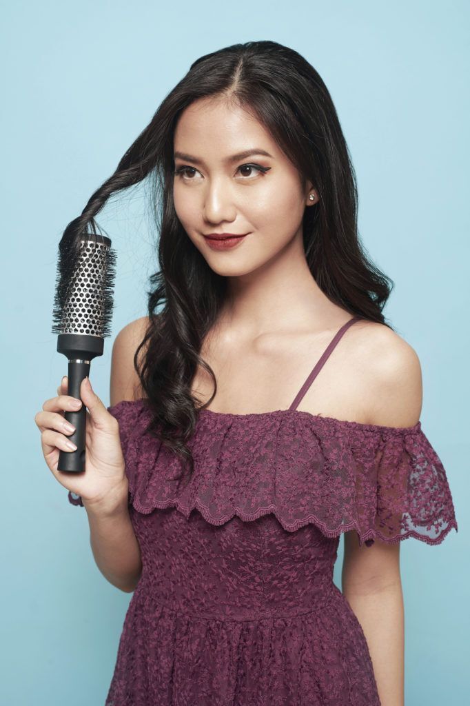 Wanita asia dengan rambut hitam menata rambut model blow dry dengan warna dress ungu