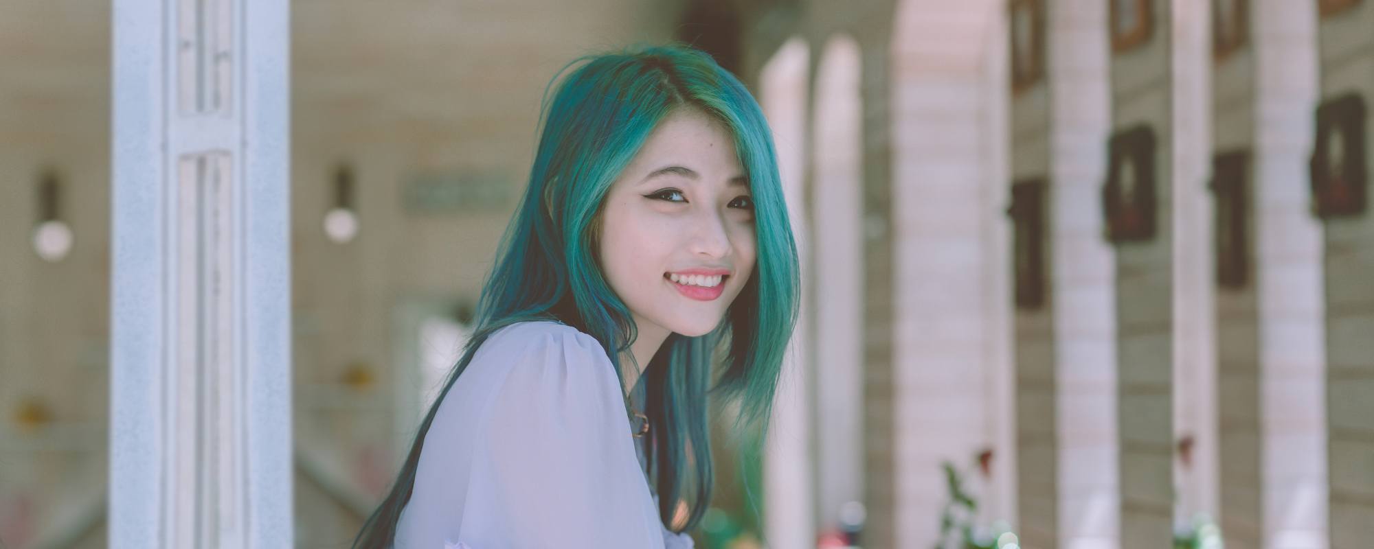 Wanita Asia dengan warna rambut hijau tosca sedang tersenyum