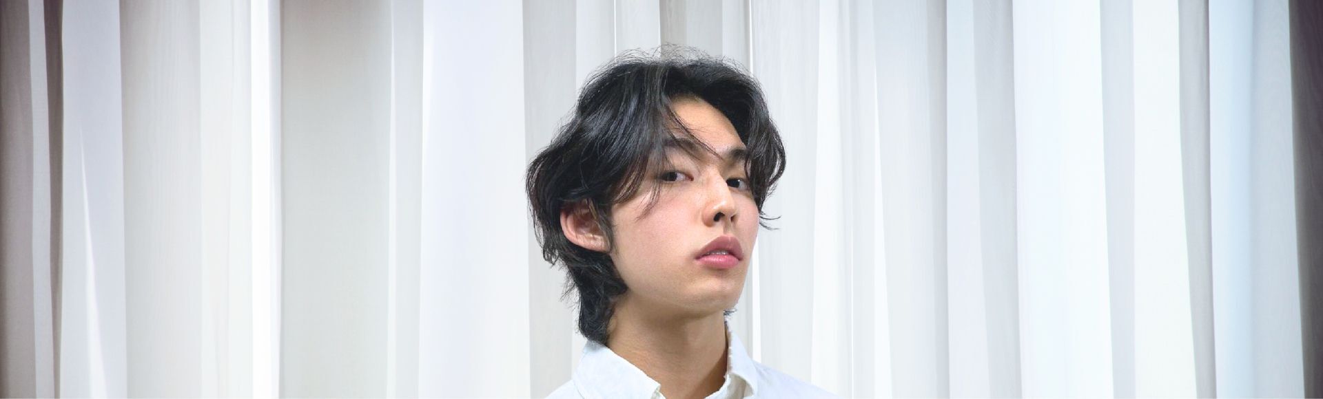 Pria Asia berambut ikal dengan gaya rambut wolf cut pendek.