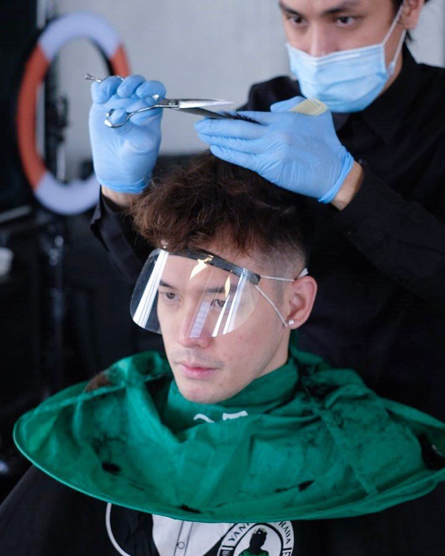 Yanus Putrada sedang menggunting rambut klien