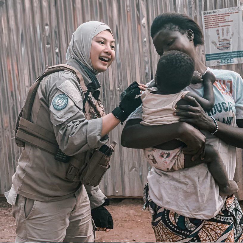 Briptu hikma mengelus anak Afrika di gendongan ibunya.