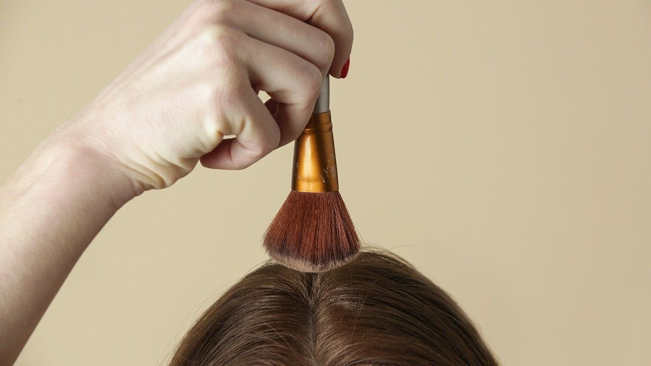 wanita sedang menggunakan bedak sebagai dry shampoo