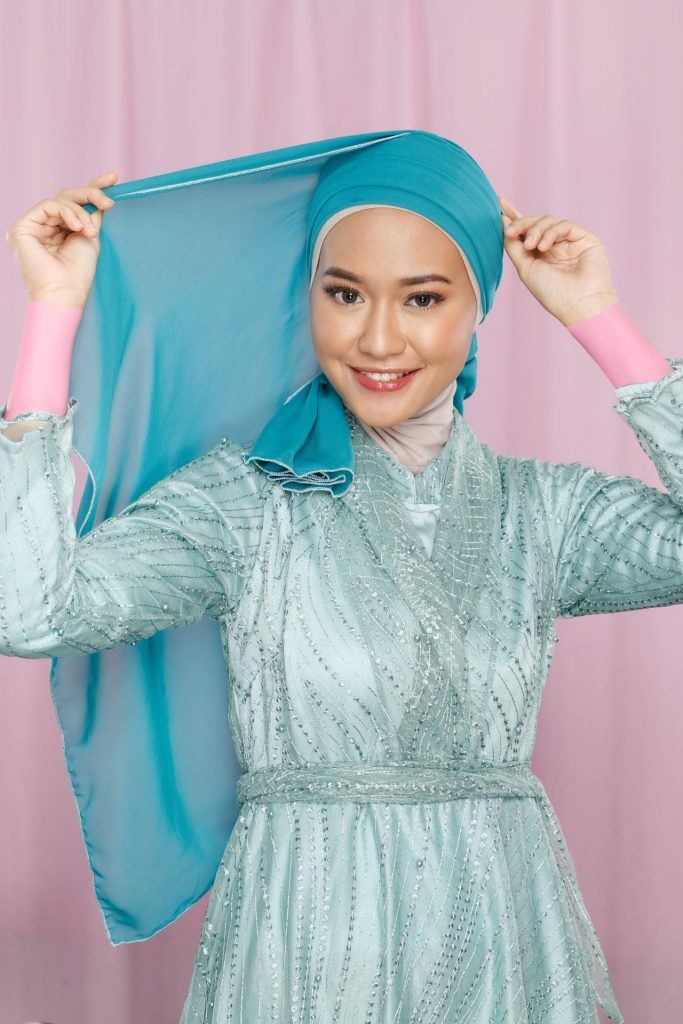 Wanita Asia memasangkan hijab hijau di kepalanya