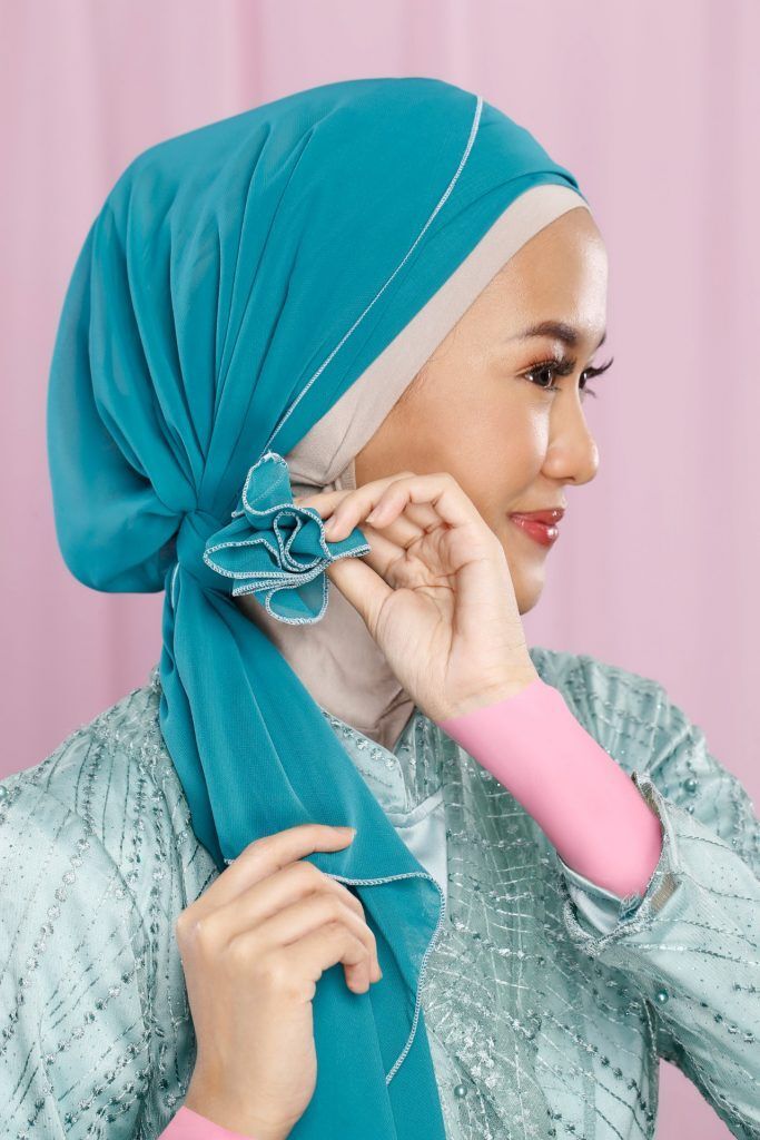 Wanita Asia mengikat hijab pashmina dengan cantik di sebelah kiri kepalanya