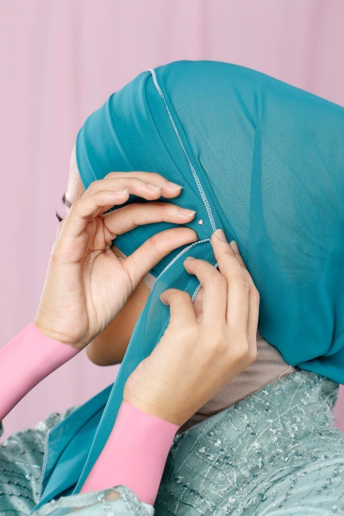 Wanita menyematkan jarum pentul di kepalanya.