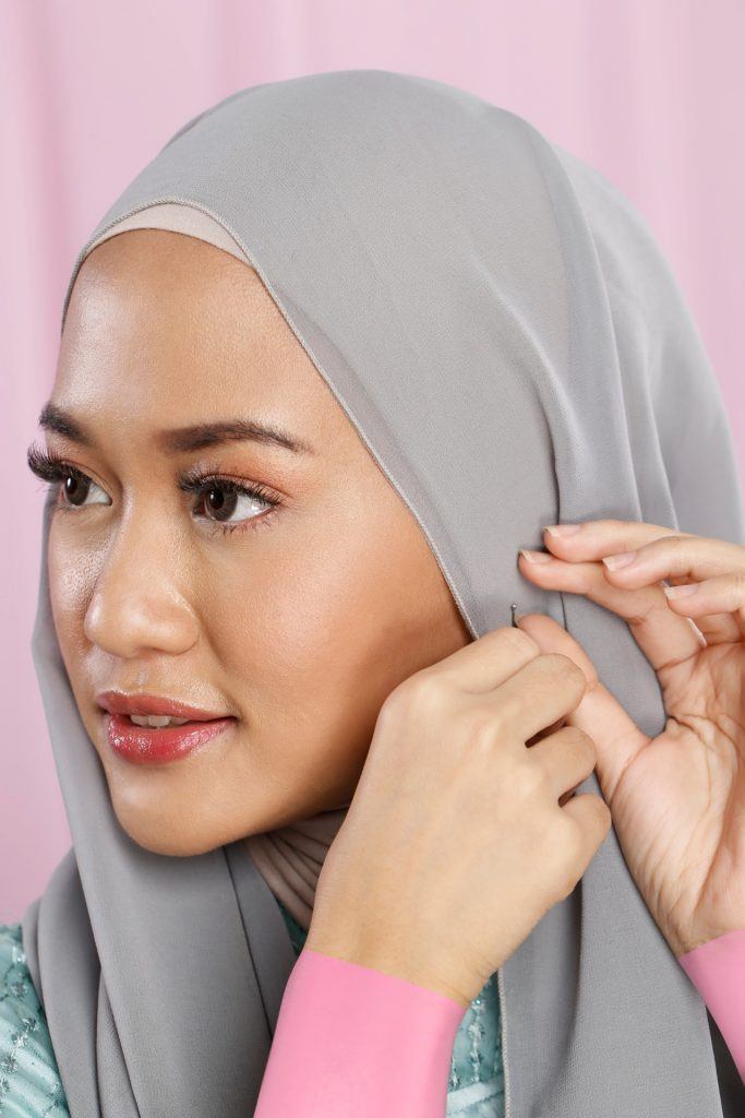 Wanita memasangkan jarum pentul di samping kepalanya