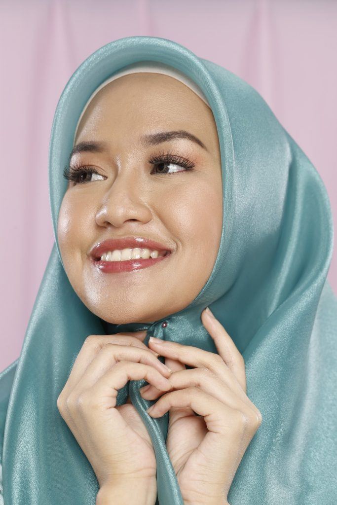 Wanita merekatkan hijab organza di kepalanya