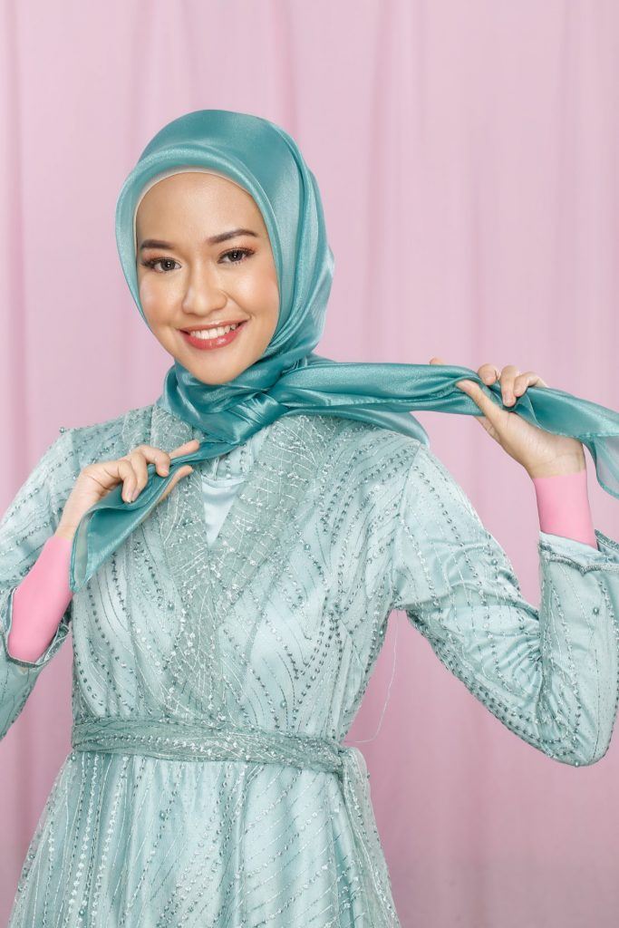 Wanita berhijab mengikat jilbab organza di lehernya.