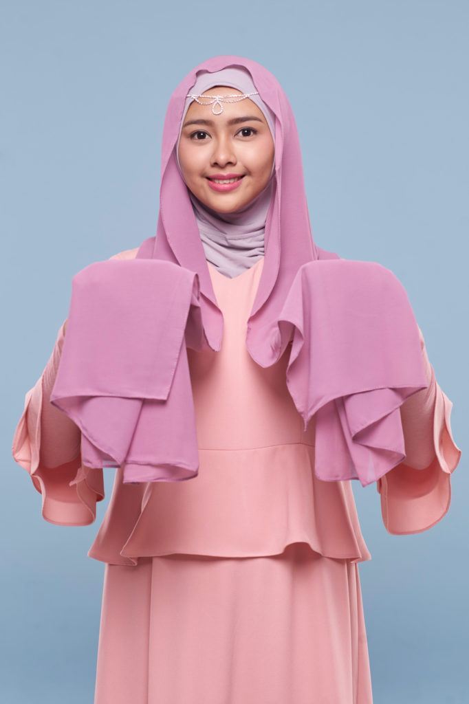 Wanita asia menggunakan hijab ungu berbahan pashmina.