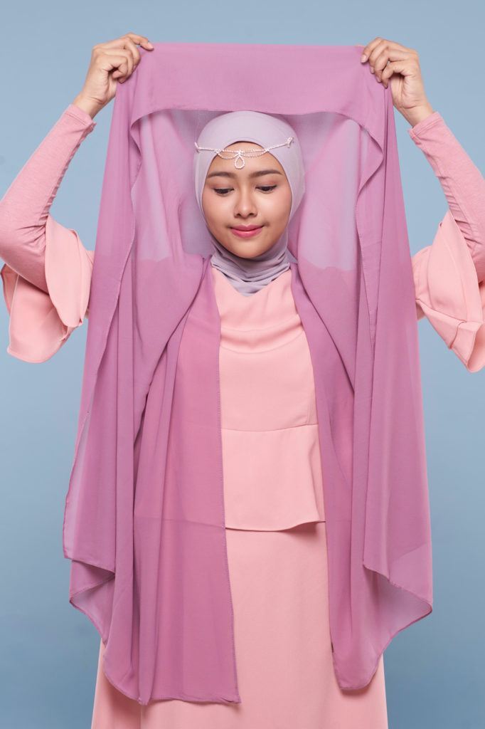 Wanita asia melipat hijab ungu ke dalam.
