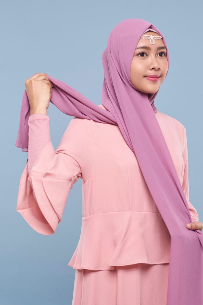 Wanita asia menyilangkan pashmina ke kiri dan kanan.