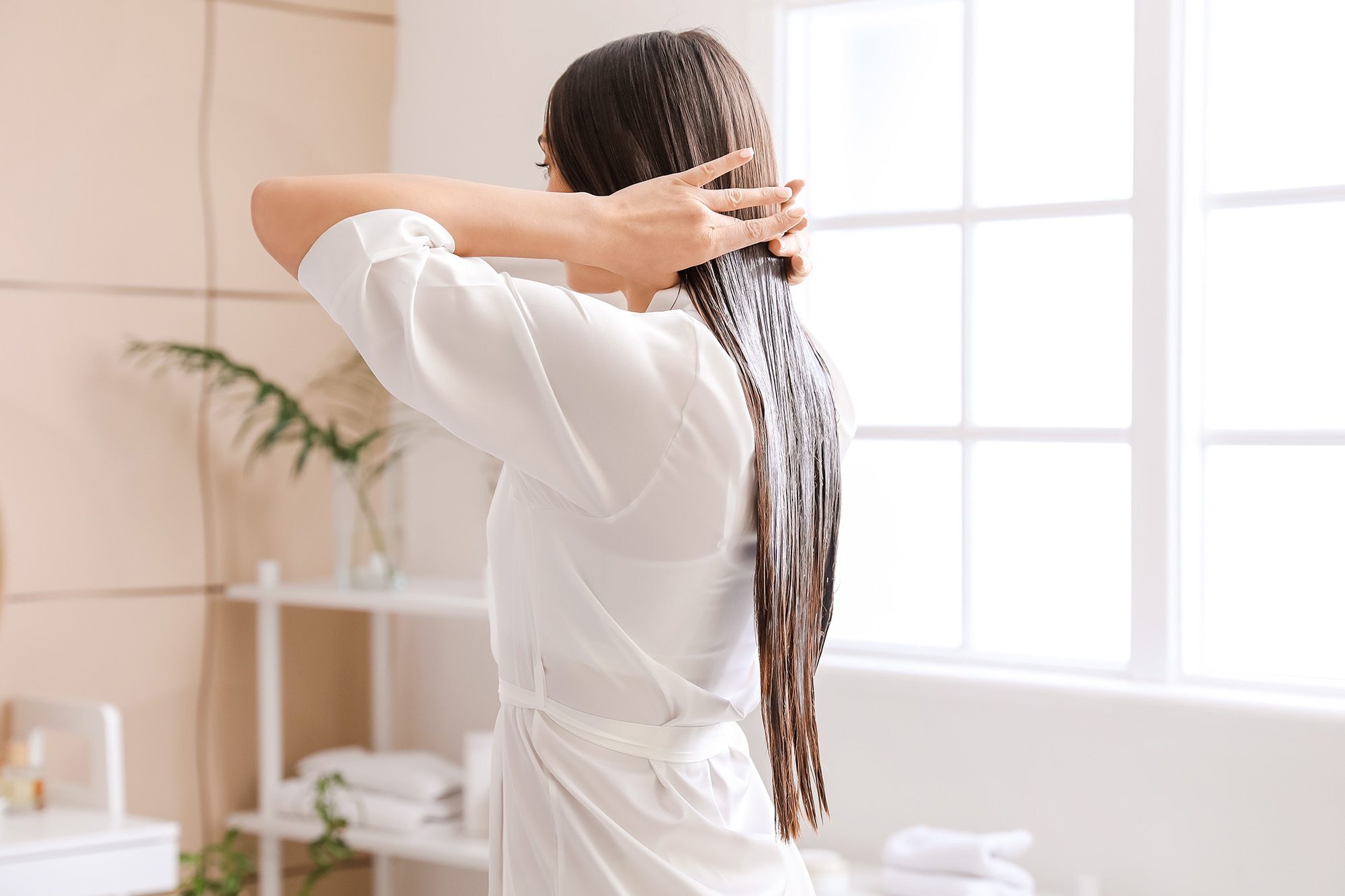 wanita dengan rambut panjang sedang menggunakan minyak kelapa pada rambut