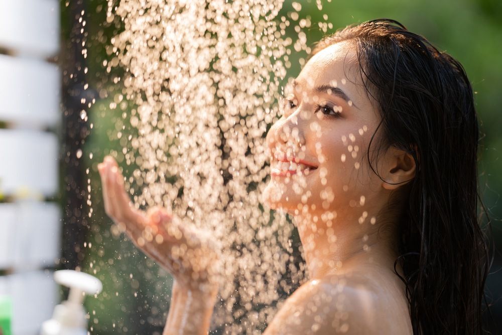 wanita asia sedang keramas dengan air dingin