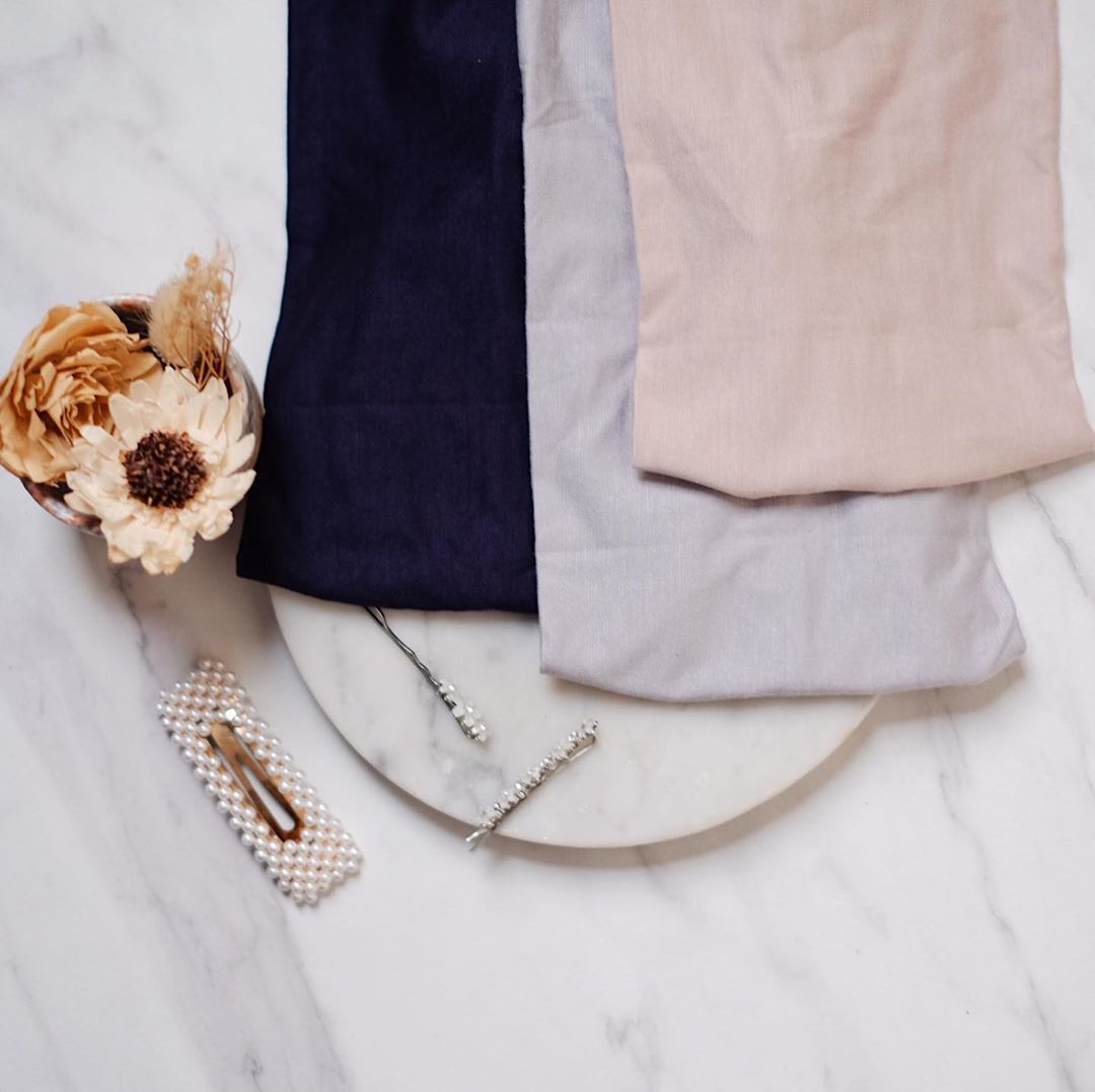 Tiga ciput bandana beda warna di atas tray marble dengan bunga dan jepit di sampingnya,