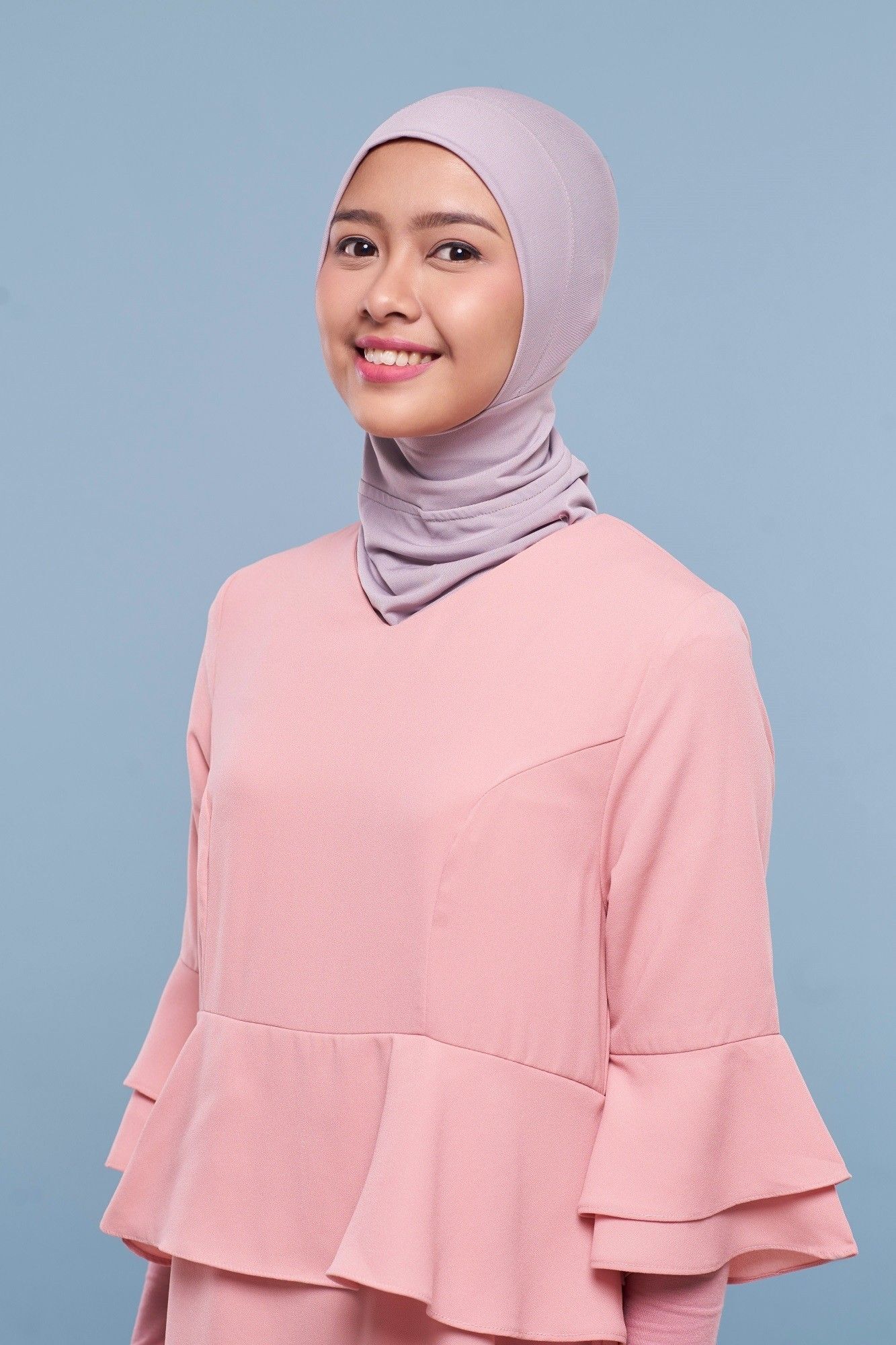 Wanita Asia memakai ciput ninja anti tembem ungu muda dan baju pink.