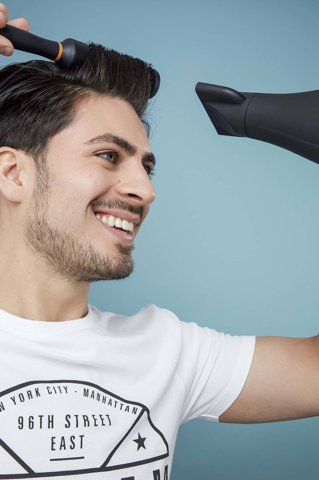 pria kaukasia sedang blow dry rambut dengan sisir bulat