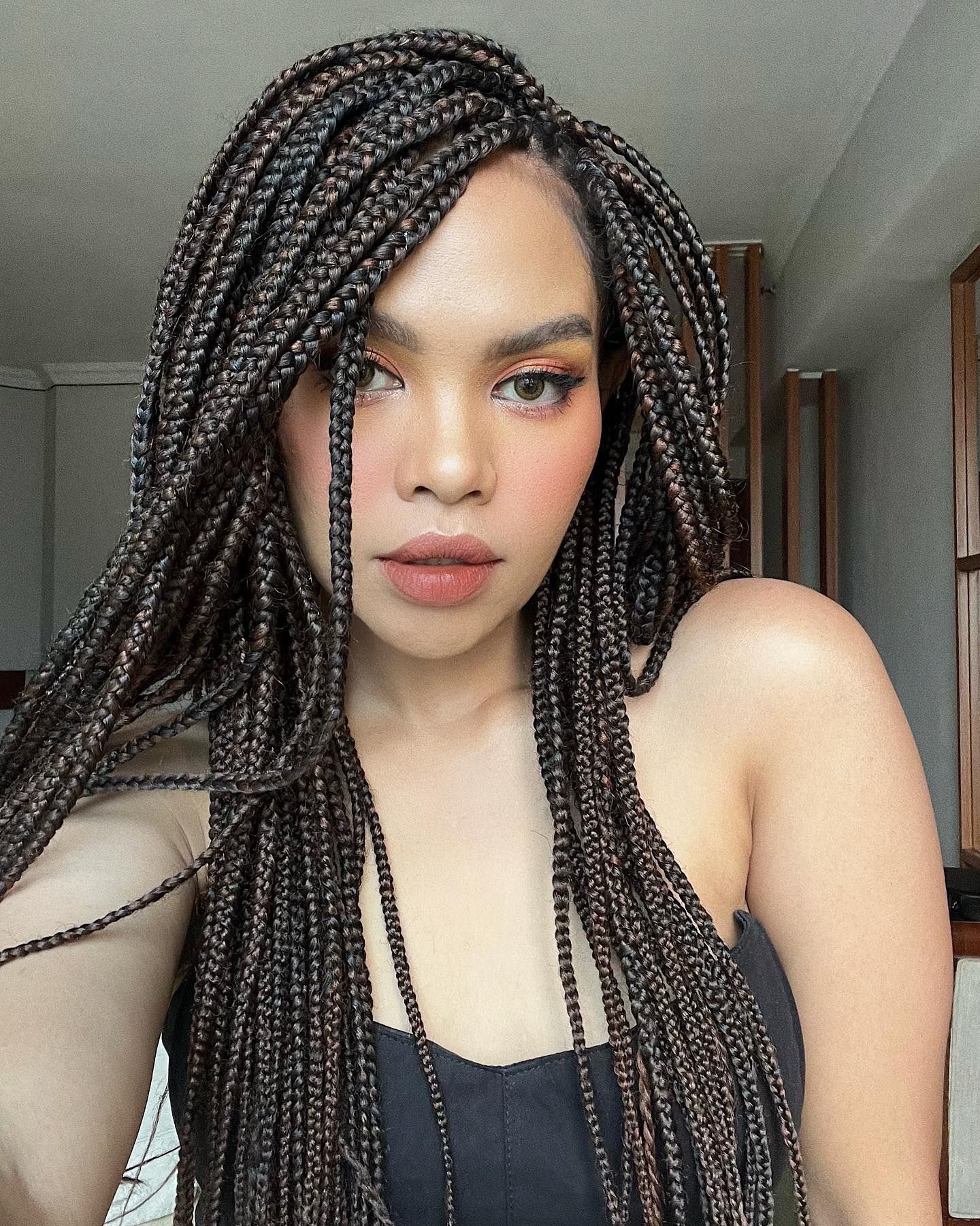 Beauty influencer, Lifni Sanders dengan gaya rambut cornrow panjang belah samping.