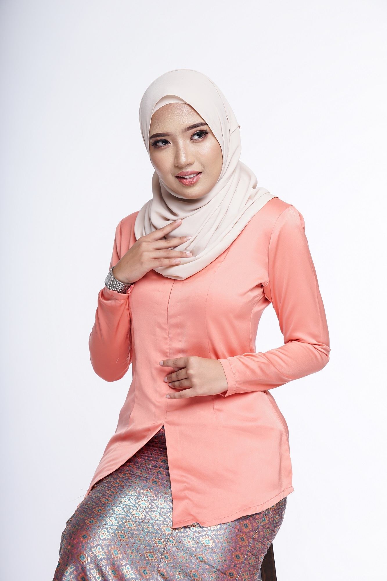 Wanita Asia memakai kebaya oranye dan pashmina