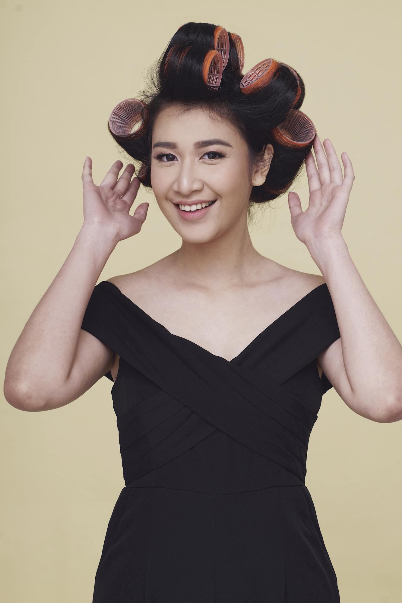 Wanita asia dengan baju hitam menggunakan hair rollers - mengatasi rambut mengembang dan kusut