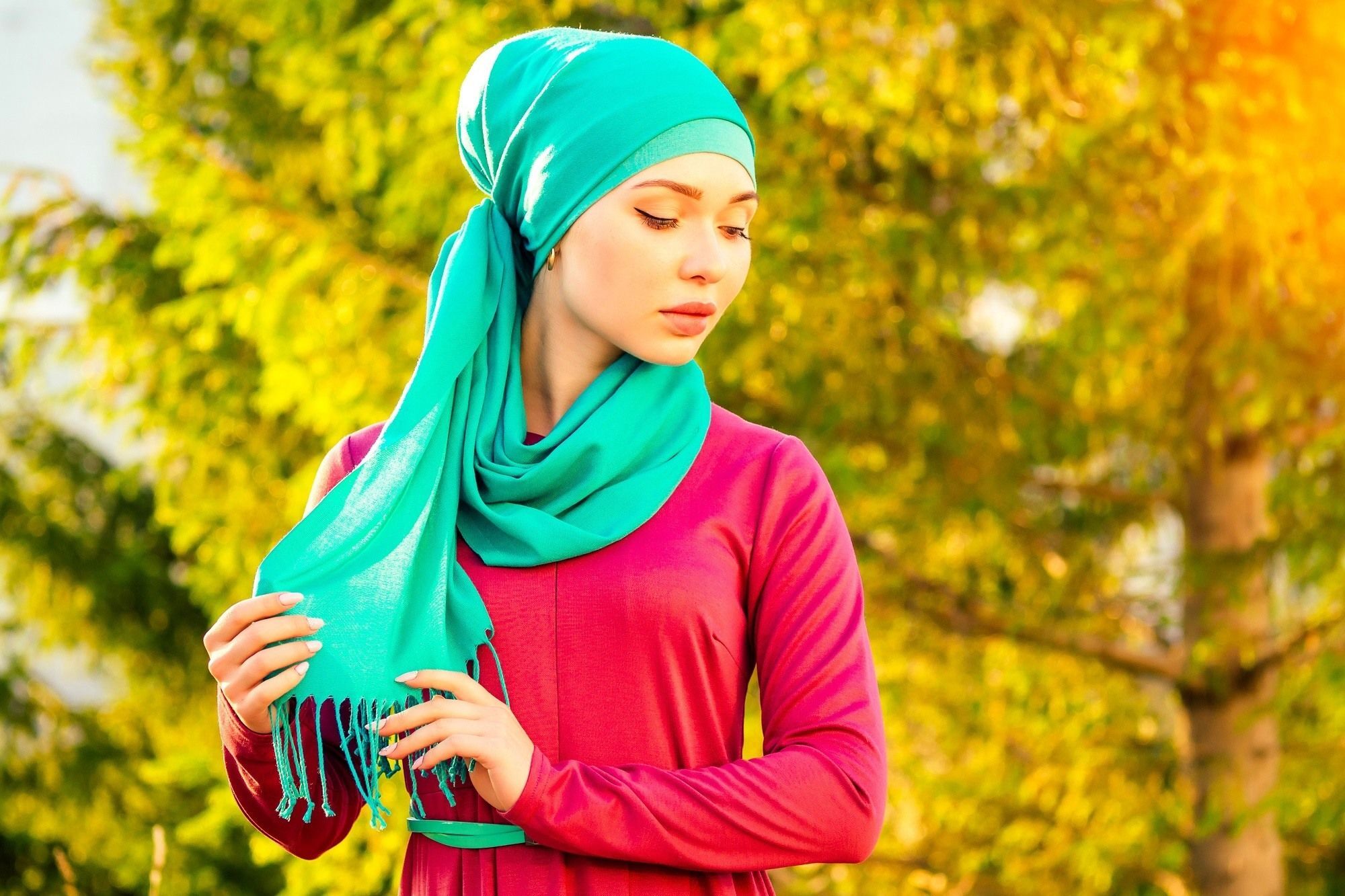 Wanita Asia memakai hijab berwarna hijau toska dengan latas pohon