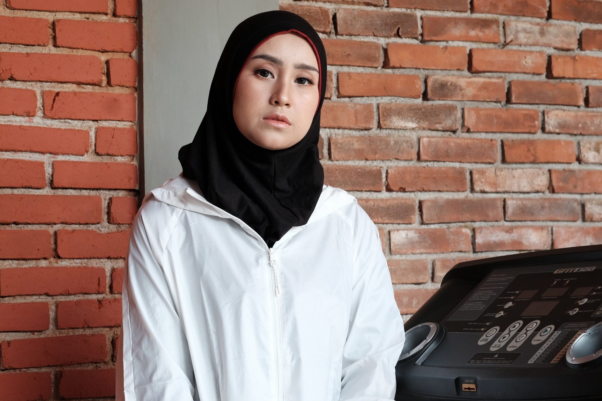 Wanita memakai hijab olahraga hitam dan jaket putih.