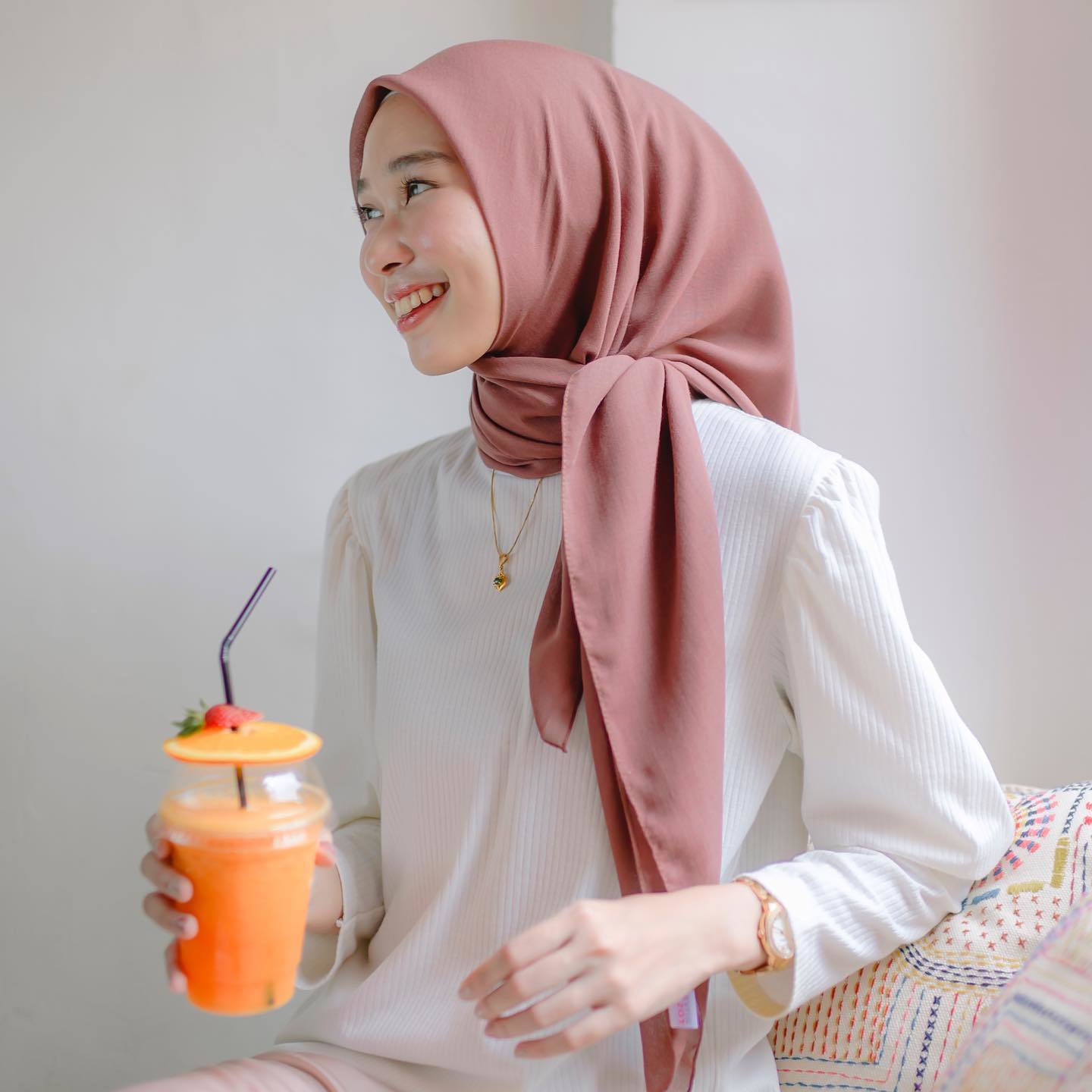 Wanita Indonesia dengan gaya hijab segi empat paris warna dusty pink.