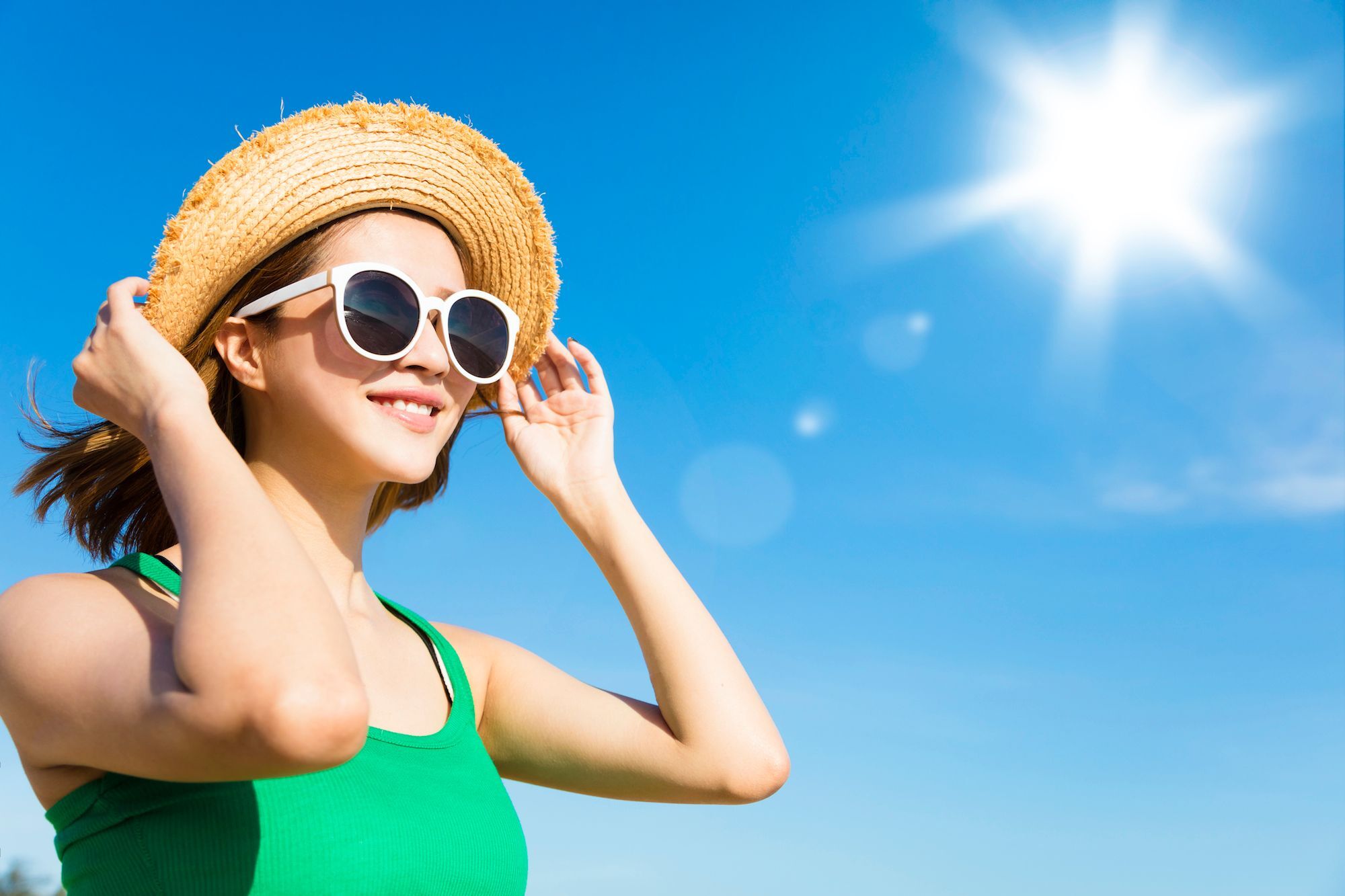 Wanita Asia dengan rambut sebahu memakai topi dan kacamata hitam.