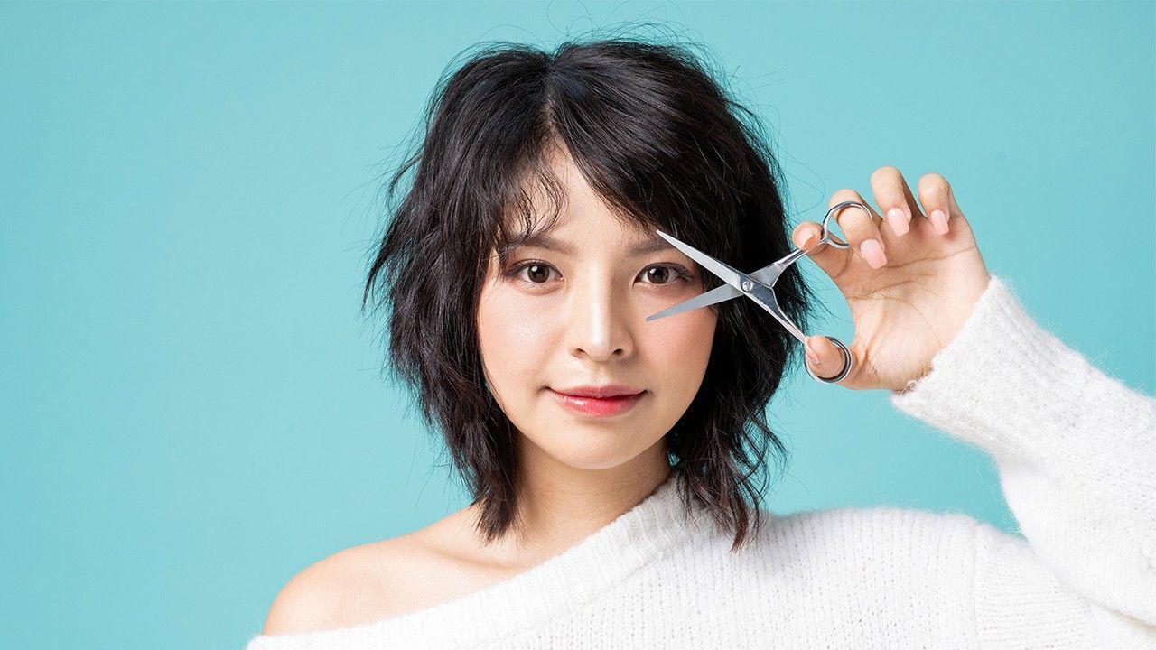 wanita asia dengan rambut pendek keriting sedang memegang gunting