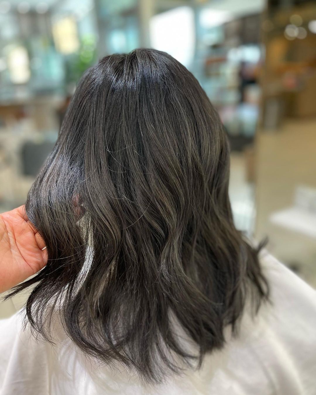 wanita dengan rambut sedang berwarna abu-abu gelap tampak belakang