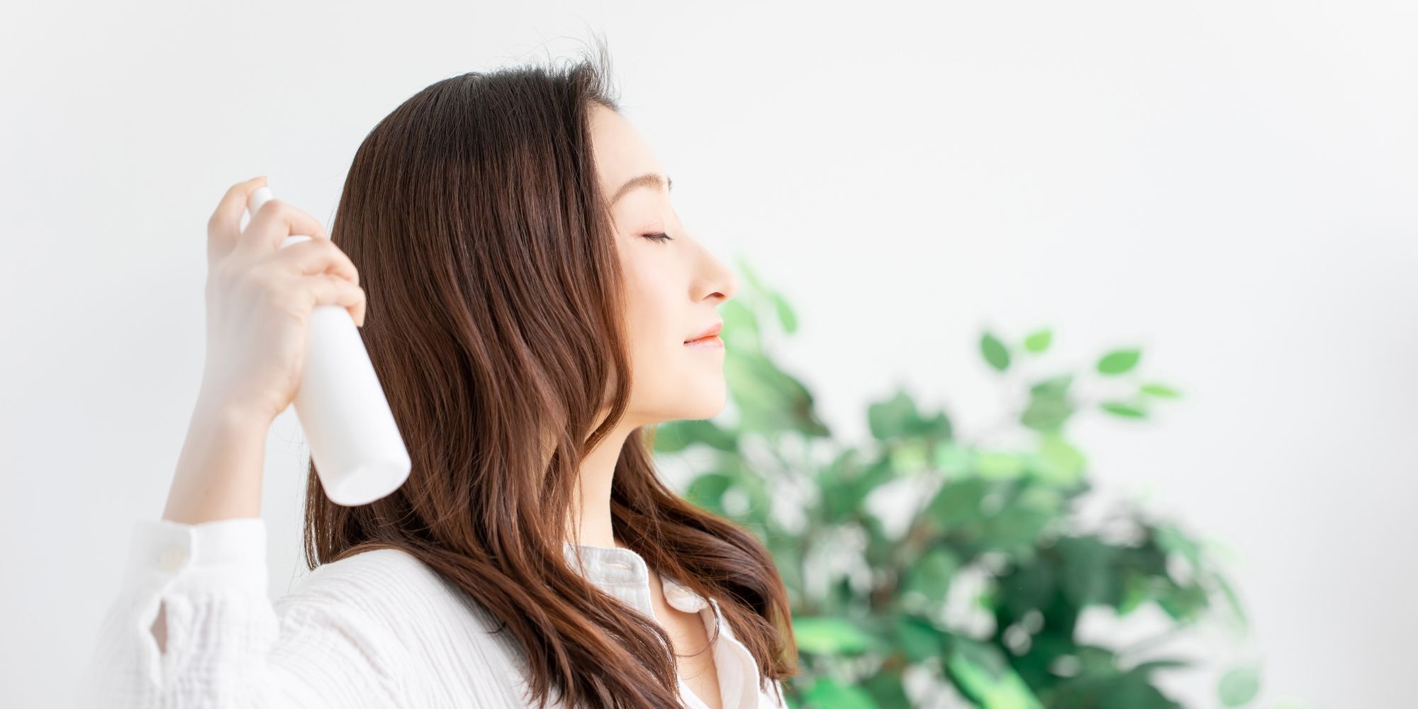 wanita asia sedang menyemprotkan spray ke rambut