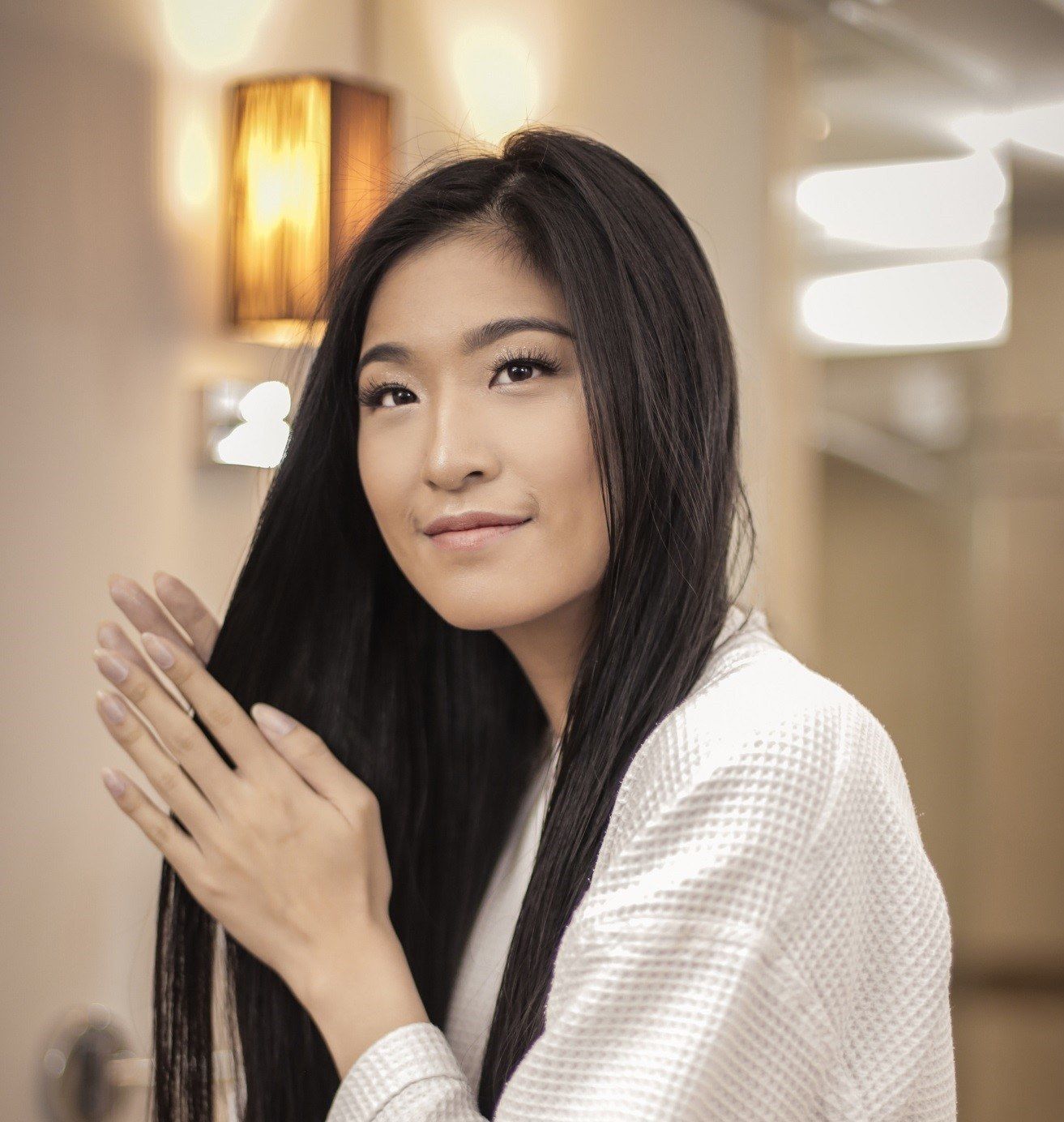 wanita asia berambut hitam mengoleskan vitamin rambut