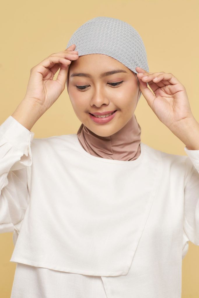 Wanita asia dengan atasan putih dan ciput abu-abu