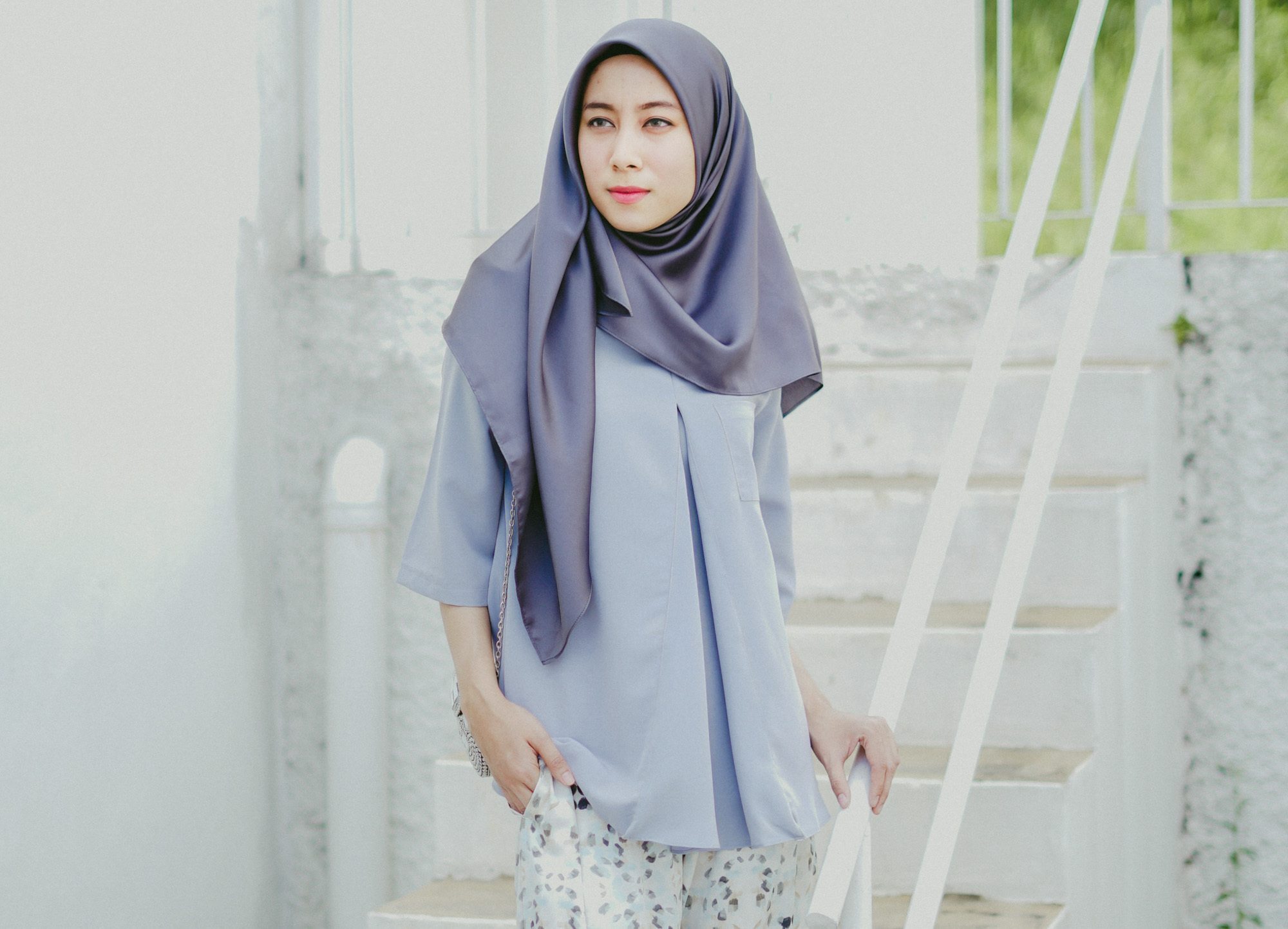 Wanita Asia memakai hijab segi empat dan blus berwarna ungu