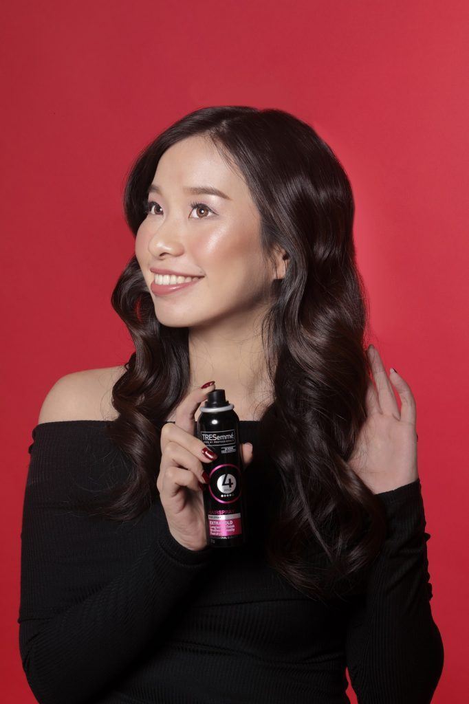 Wanita sedang menyemprot hairspray pada rambut ala Hollywood wave gaya klasik