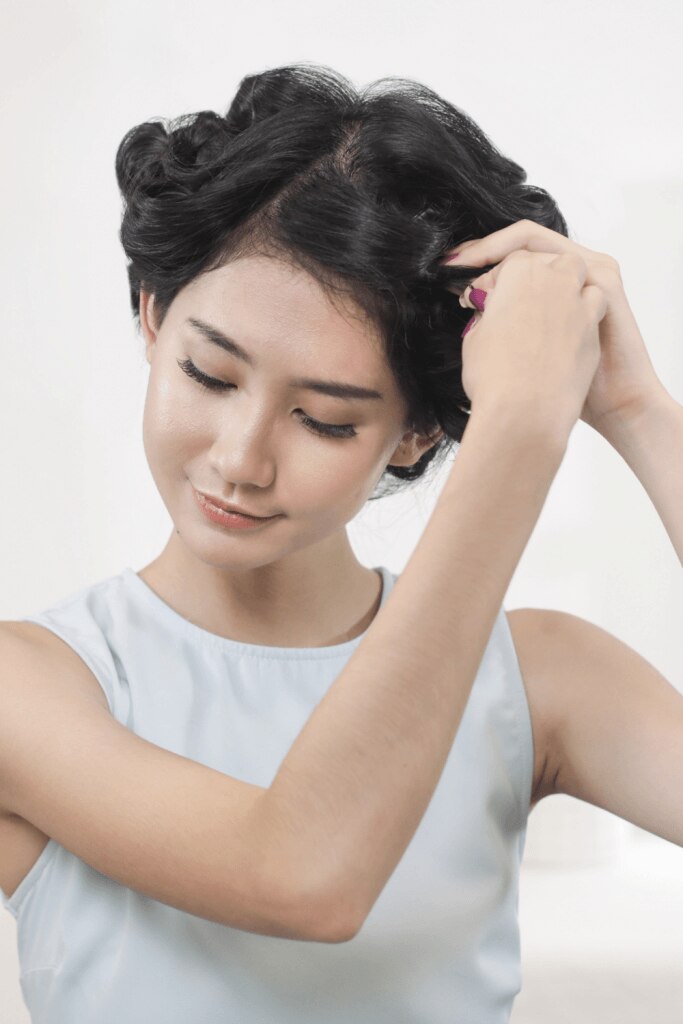 wanita asia sedang menata rambut dan menggulung rambut bergelombang