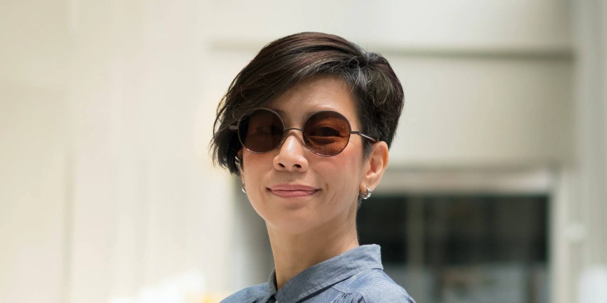 wanita asia dengan rambut pixie dan memakai kacamata hitam