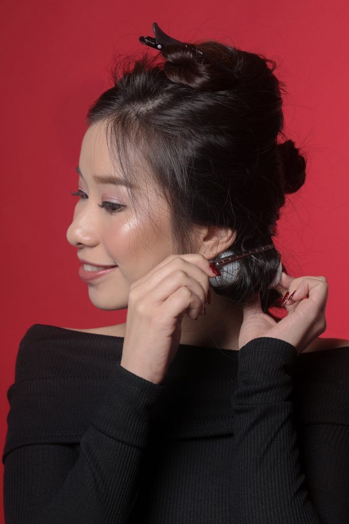 Wanita sedang memasangkan roll rambut