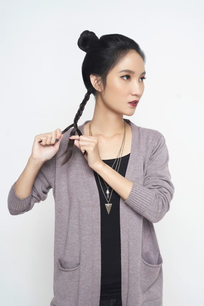 Wanita asia dengan model rambut sanggul kepang warna hitam sedang mengepang rambut