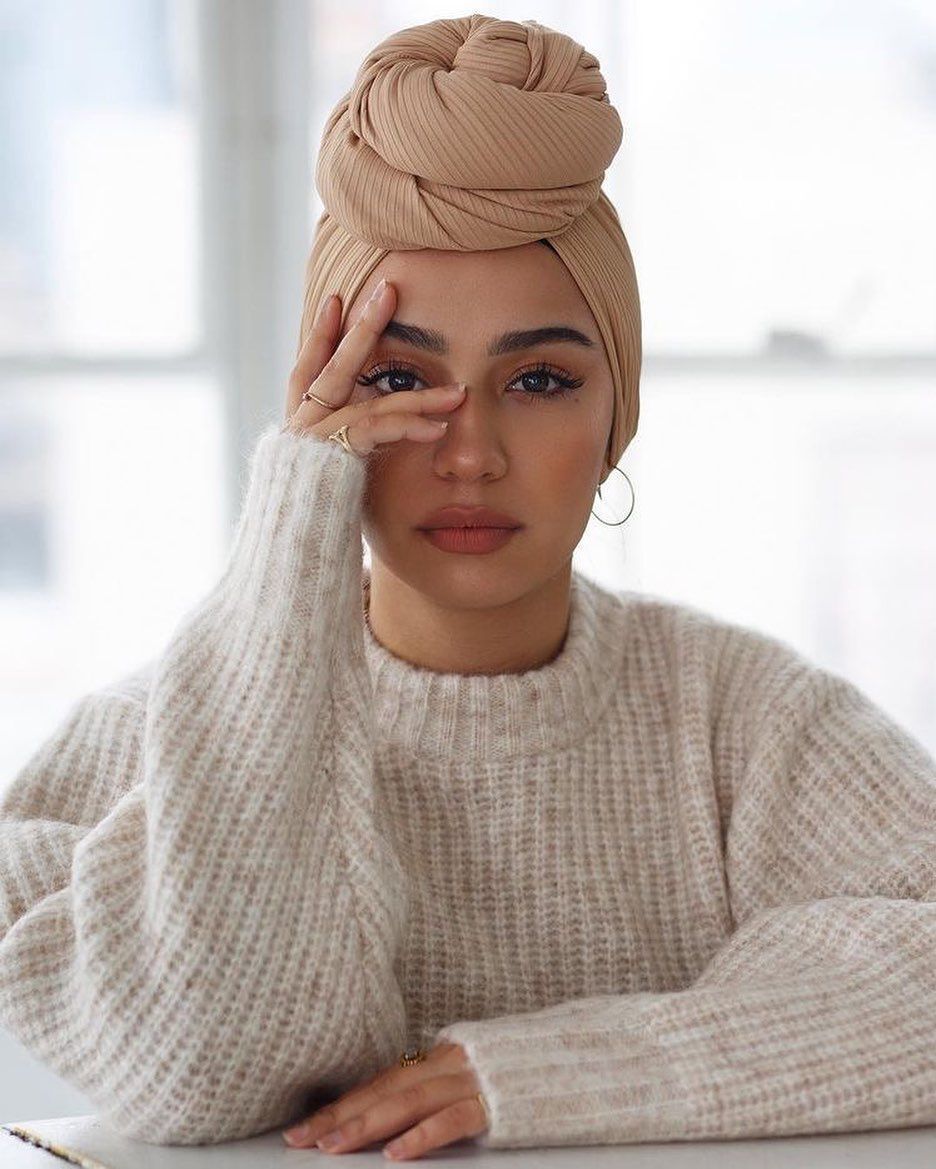 wanita kaukasia dengan pose menutup sebagian mata memakai gaya hijab turban lilit.