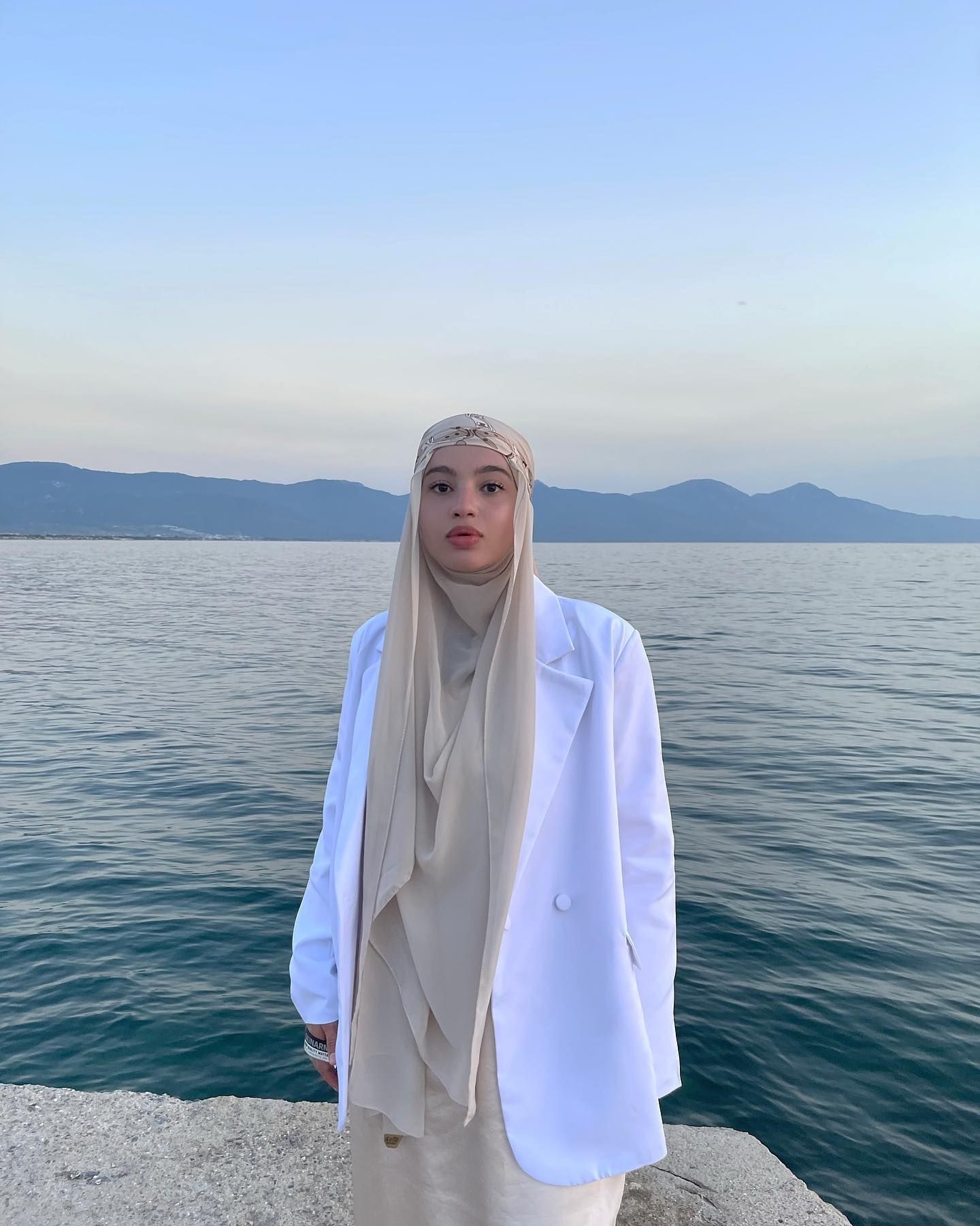 Wanita kaukasia mengenakan padanan hijab pashmina dengan aksen turban scarf bermotif