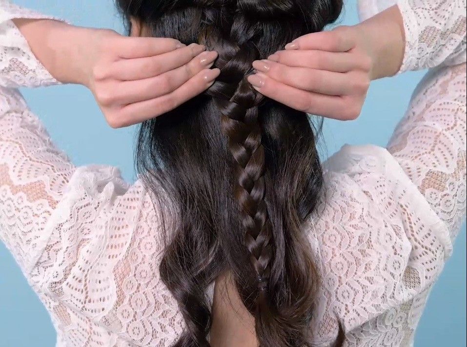 Wanita sedang melonggarkan kepangan rambut.