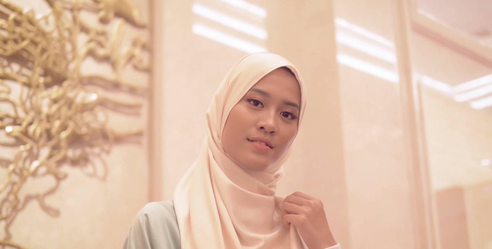 Wanita berhijab sedang duduk dan mengetik sesuatu di laptop nya