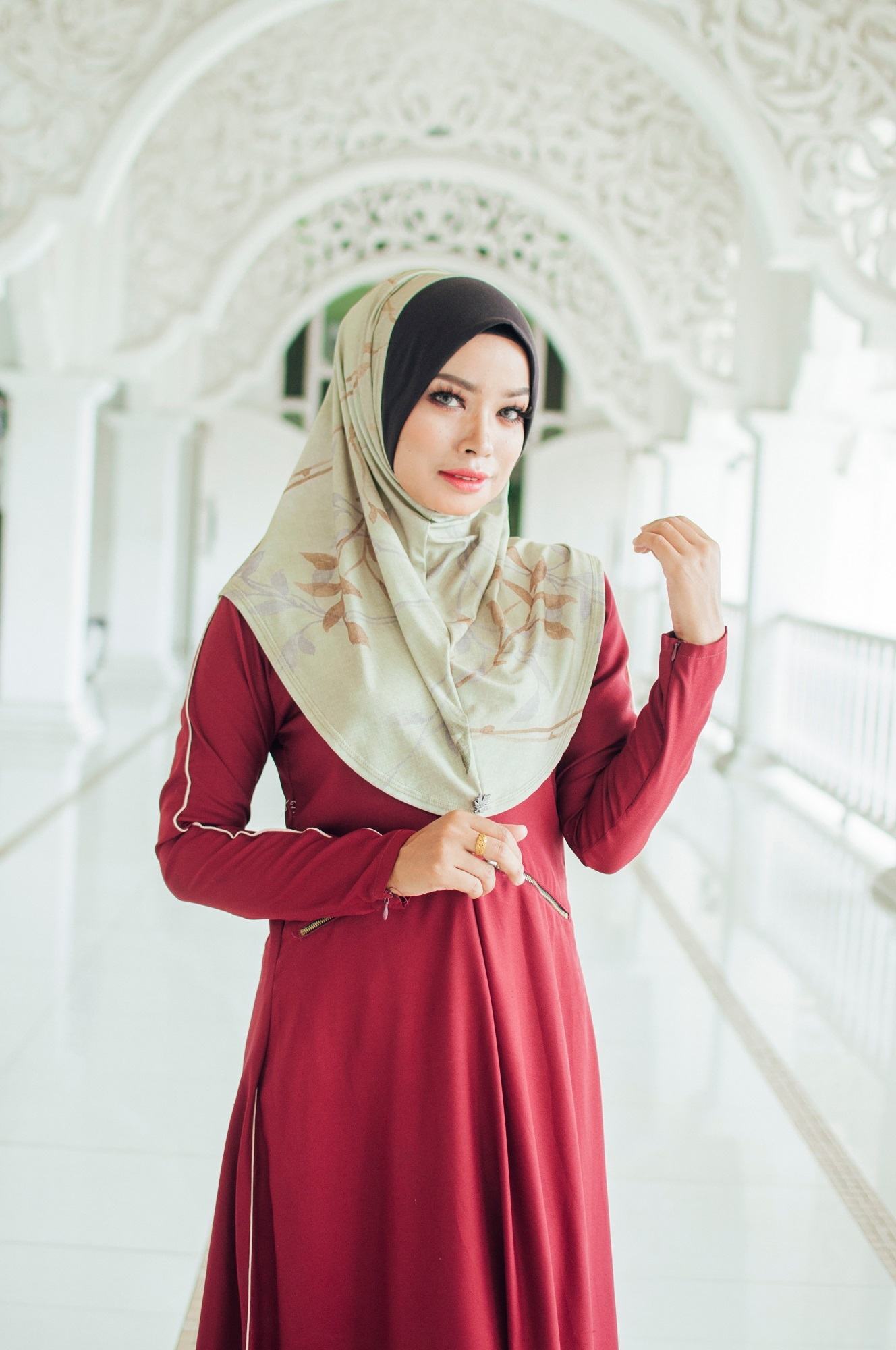 Wanita Asia memakai hijab instan hijau dan baju merah.